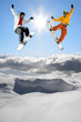 Snowboarders jumping against blue sky