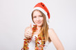 Girl in Santa hat showing thumbs up.