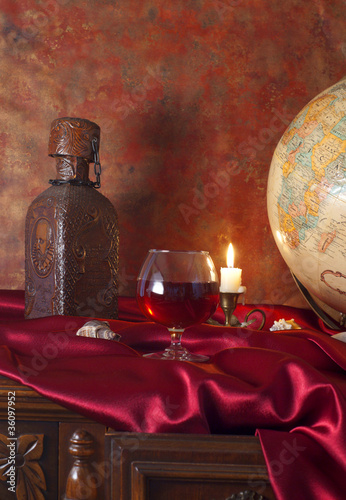 Photo: Glass of brandy and globe on an antique table Glass of brandy and globe on an antique table