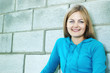 Foto: smiling blue-eyed young woman against blurred wall smiling blue-eyed young woman against blurred wall