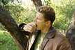 A man in a garden eats a green apple