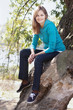 Foto: Sporty blue-eyed smiling woman sitting on a tree Sporty blue-eyed smiling woman sitting on a tree