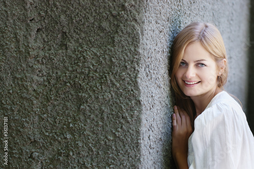 Foto: Beautiful blue-eyed smiling woman against rough wall Beautiful blue-eyed smiling woman against rough wall