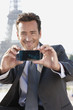 Foto: Businessman taking a picture of himself with the Eiffel Tower in the background, Paris, Ile-de-France, France Businessman taking a picture of himself with the Eiffel Tower in the background, Paris, Ile-de-France, France