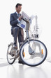 Foto: Businessman reading a newspaper on a bicycle with the Eiffel Tower in the background, Paris, Ile-de-France, France Businessman reading a newspaper on a bicycle with the Eiffel Tower in the background, Paris, Ile-de-France, France