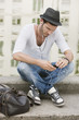 Photo: Man sitting on the ledge of a canal and listening to music with an MP3 player, Paris, Ile-de-France, France Man sitting on the ledge of a canal and listening to music with an MP3 player, Paris, Ile-de-France, France