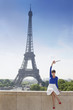 Foto: Woman holding a replica of Eiffel Tower sitting on a stone wall with the Eiffel Tower in the background, Paris, Ile-de-France, France Woman holding a replica of Eiffel Tower sitting on a stone wall with the Eiffel Tower in the background, Paris, Ile-de-France, France