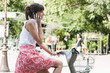 Photo: Woman riding a bicycle and talking on a mobile phone, Paris, Ile-de-France, France Woman riding a bicycle and talking on a mobile phone, Paris, Ile-de-France, France