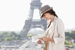Foto: Woman reading a guide book with the Eiffel Tower in the background, Paris, Ile-de-France, France Woman reading a guide book with the Eiffel Tower in the background, Paris, Ile-de-France, France