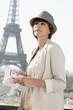 Foto: Woman holding a guide book with the Eiffel Tower in the background, Paris, Ile-de-France, France Woman holding a guide book with the Eiffel Tower in the background, Paris, Ile-de-France, France