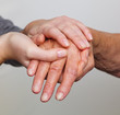 Alte und junge Hand mit Gehstock