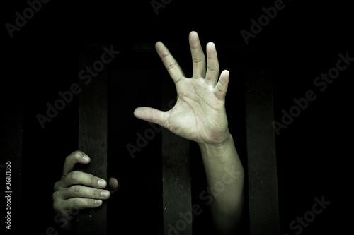 Photo: Human hand stretch out from prison bars Human hand stretch out from prison bars