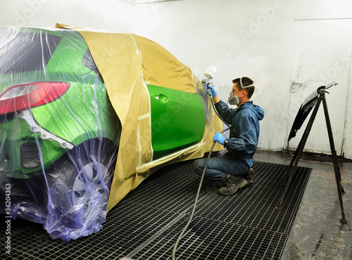 Photo: Worker painting a car. Worker painting a car.