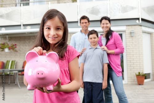 Photo: Girl saving money with family at the back Girl saving money with family at the back