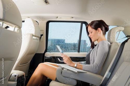 Photo: Executive businesswoman in car work touch tablet Executive businesswoman in car work touch tablet