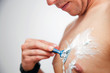 Young man shaving his chest, torso