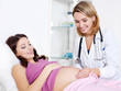 The doctor touches the stomach of a young pregnant woman