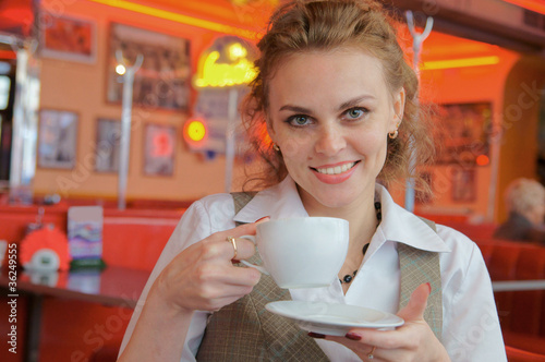 Foto: Young pretty woman in street cafe with cup Young pretty woman in street cafe with cup