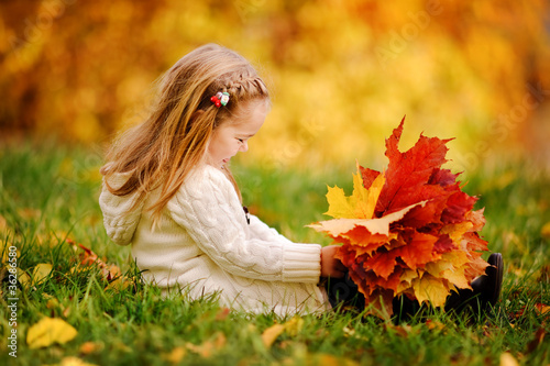 Photo: toddler girl have fun playing with fallen golden leaves toddler girl have fun playing with fallen golden leaves