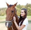 Beautiful young woman is brushing a gorgeous horse