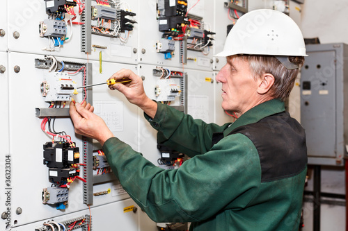 Photo: Electrician working in white helmet with cables and screwdriver Electrician working in white helmet with cables and screwdriver