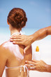Man applying sunscreen lotion on woman's back