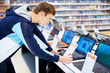Young man in consumer electronic store looks at laptop
