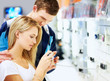 Young couple checking out new digital camera at store Young couple checking out new digital camera at store