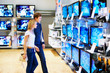Foto: Young couple in electronics store looking at TVs Young couple in electronics store looking at TVs