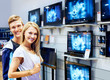 Young couple in electronics store looking at TVs