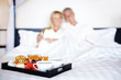 Portrait of happy mature couple on bed with breakfast in front Portrait of happy mature couple on bed with breakfast in front