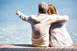 Romantic couple sitting on a boardwalk while man pointing