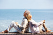Portrait of a happy mature couple sitting back to back on a pier