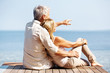 Rear view of man sitting on wooden pier with his wife
