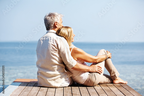 Photo: Couple sitting on pier spending romantic time together Couple sitting on pier spending romantic time together