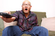 Asian man with remote watching television.