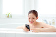 スマートフォンを持って入浴する女性