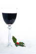 Glass of red wine with holly in the snow Glass of red wine with holly in the snow