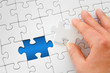 Hand fügt das fehlende Puzzleteil hinzu