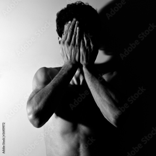 Photo: Portrait of a young man covering his face in hands Portrait of a young man covering his face in hands