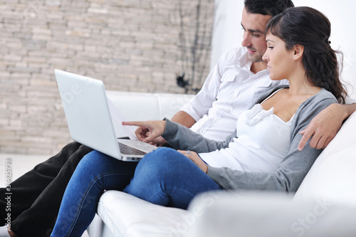 Photo: joyful couple relax and work on laptop computer at modern home joyful couple relax and work on laptop computer at modern home