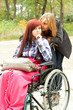 invalid girl on the wheelchair with friend outdoors