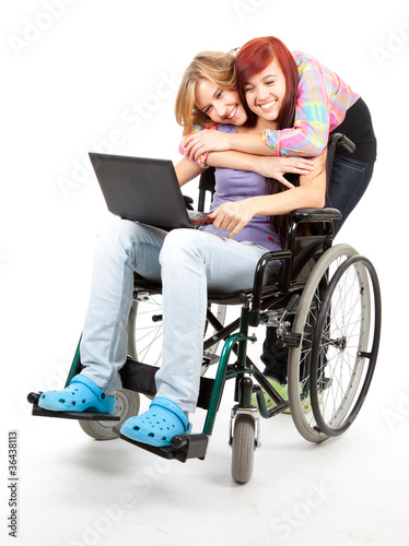 Photo: invalid girl on the wheelchair with laptop and friend invalid girl on the wheelchair with laptop and friend