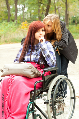 Photo: invalid girl on the wheelchair with friend outdoors invalid girl on the wheelchair with friend outdoors