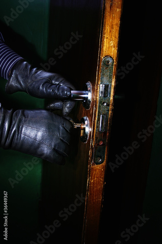Photo: hands in leather gloves of a burglar opening a door hands in leather gloves of a burglar opening a door