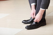 Man ties his shiney new black leather business shoes.