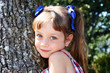 Little girl leaning on tree