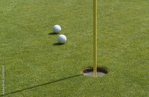 Foto: hole and golf balls in green back hole and golf balls in green back