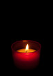 Red candle burning in the dark, black background Red candle burning in the dark, black background