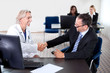 Doctor shaking hands with a patient at a desk